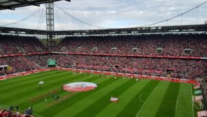 Fußballstadion des FC-Bayern Münchens mit grünem Rasen und gefüllten Tribünen.