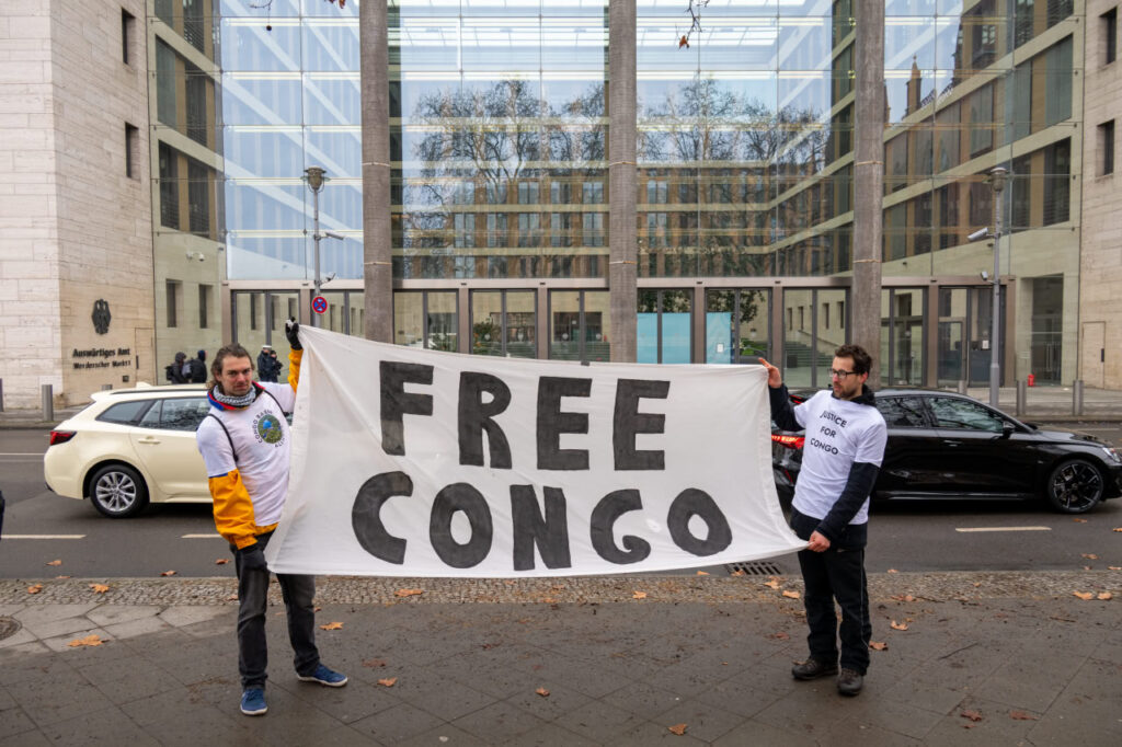 Ein Banner mit der Aufschrift "Free Congo" wird vor dem auswärtigen Amt ausgebreitet.