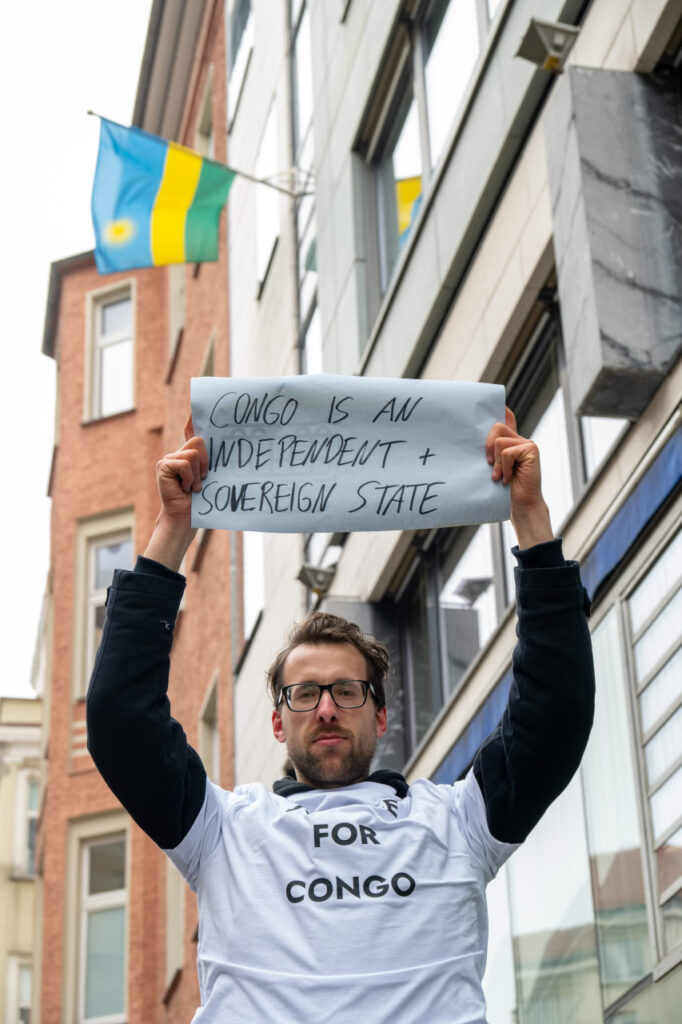 Eine Person hält ein Plakat vor der Ruandischen Botschaft mit der Aufschrift "Congo is an indepentent and sovereign state".
